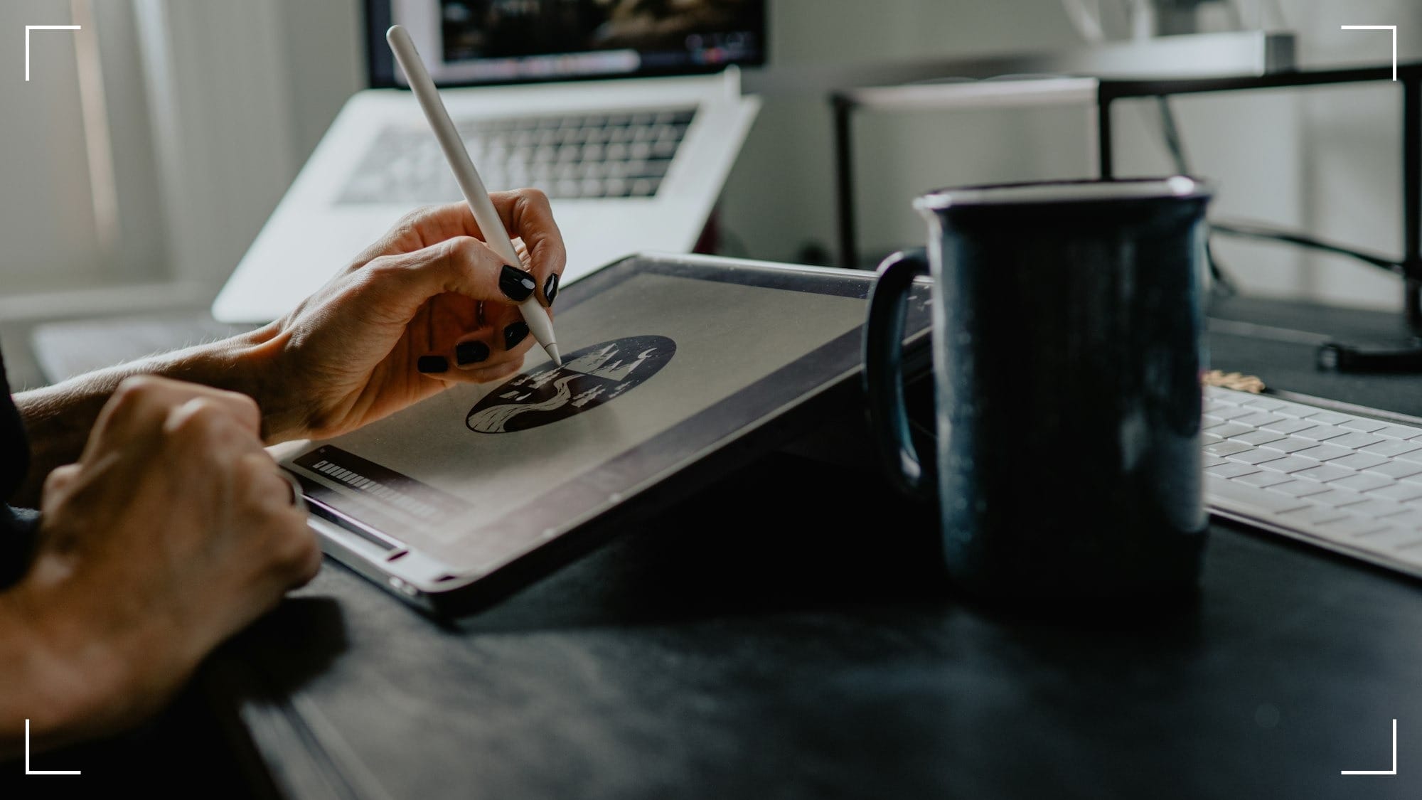 A close up shot of a desktop where a person is using a stylus to draw on a tablet. There is a cup of coffee and a keyboard nearby.
