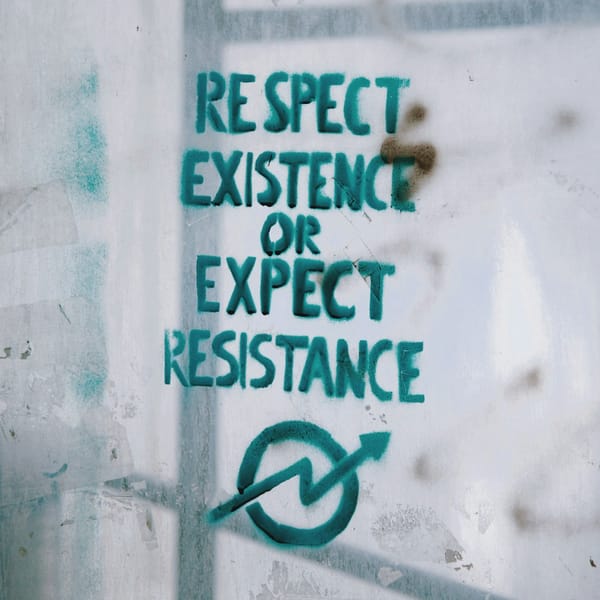 Graffiti on a wall reads: "Respect existence or expect resistance" in teal letters, with a circle and arrow symbol below.