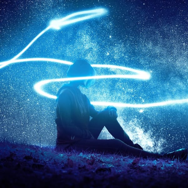 A person sits on grass under a starry sky, surrounded by glowing blue light trails.